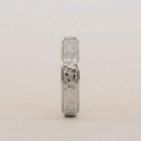 Silver ring with a textured band on a light gray background