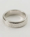 Silver ring with textured band on a white background