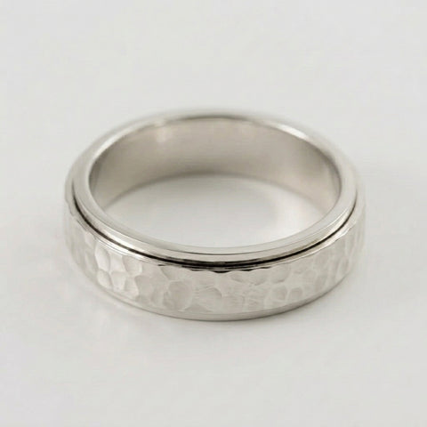 Silver ring with textured band on a white background