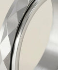 Close-up of a silver ring with geometric design on a neutral background