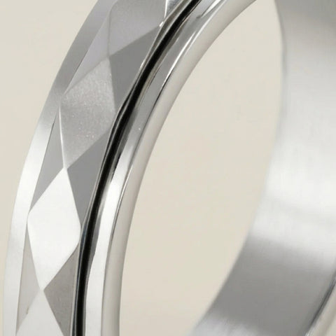 Close-up of a silver ring with geometric design on a neutral background