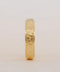 Gold ring with a textured band on a light gray background