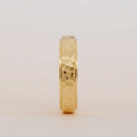 Gold ring with a textured band on a light gray background