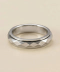 Silver ring with geometric pattern on a beige background