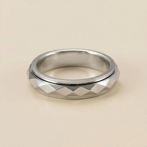Silver ring with geometric pattern on a beige background