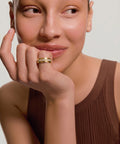 Woman wearing a gold ring on her finger against a neutral background