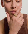Woman wearing a gold ring on her finger with a neutral background