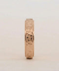 Gold ring with a textured band on a light gray background