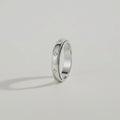 Silver ring with embedded diamonds on a light gray background