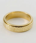 Gold ring with a textured band on a white background