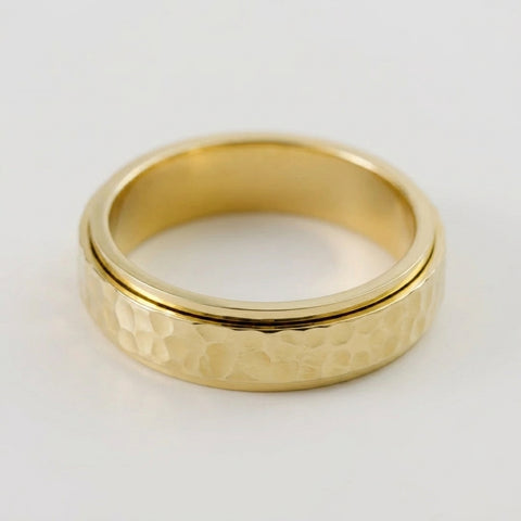 Gold ring with a textured band on a white background