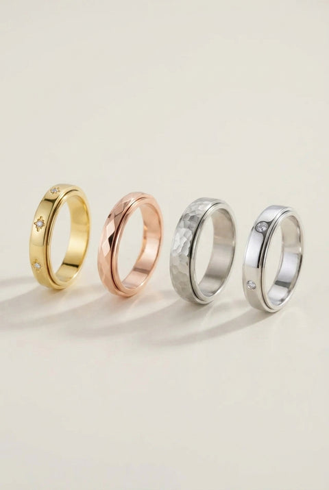 Four gold rings of different colors on a light beige background