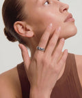 Woman wearing a ring on her finger against a neutral background